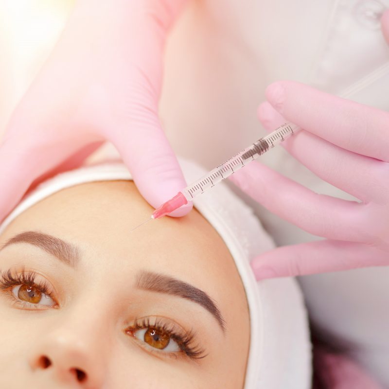 Woman gets injection in her face. Beauty woman giving botox injections. Young woman gets beauty facial injections in the cosmetology salon. Face aging injection. Aesthetic Medicine, Cosmetology